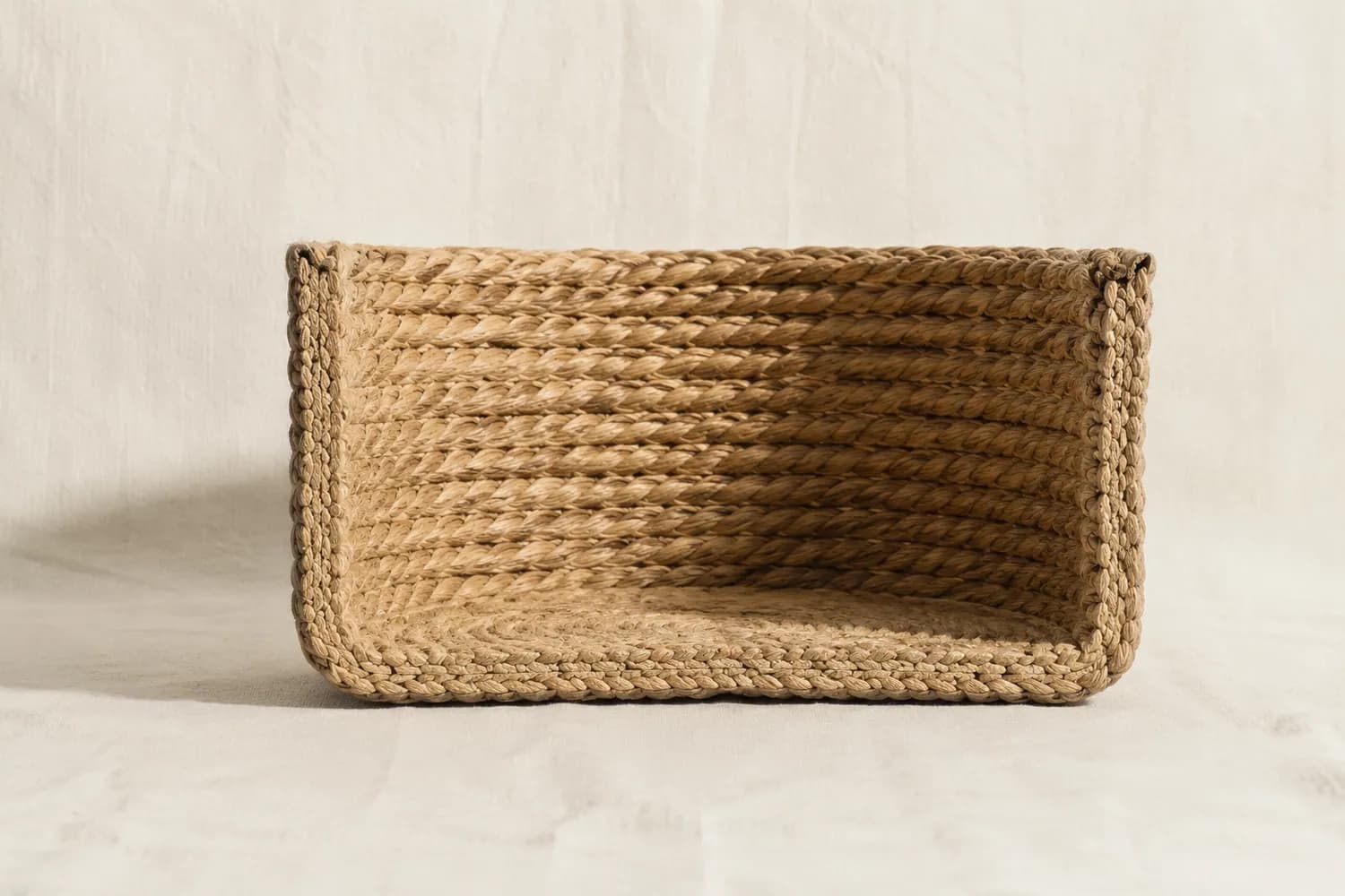 A round woven basket cut vertically in half, showing the thickness of the woven wall and the hollow interior space.